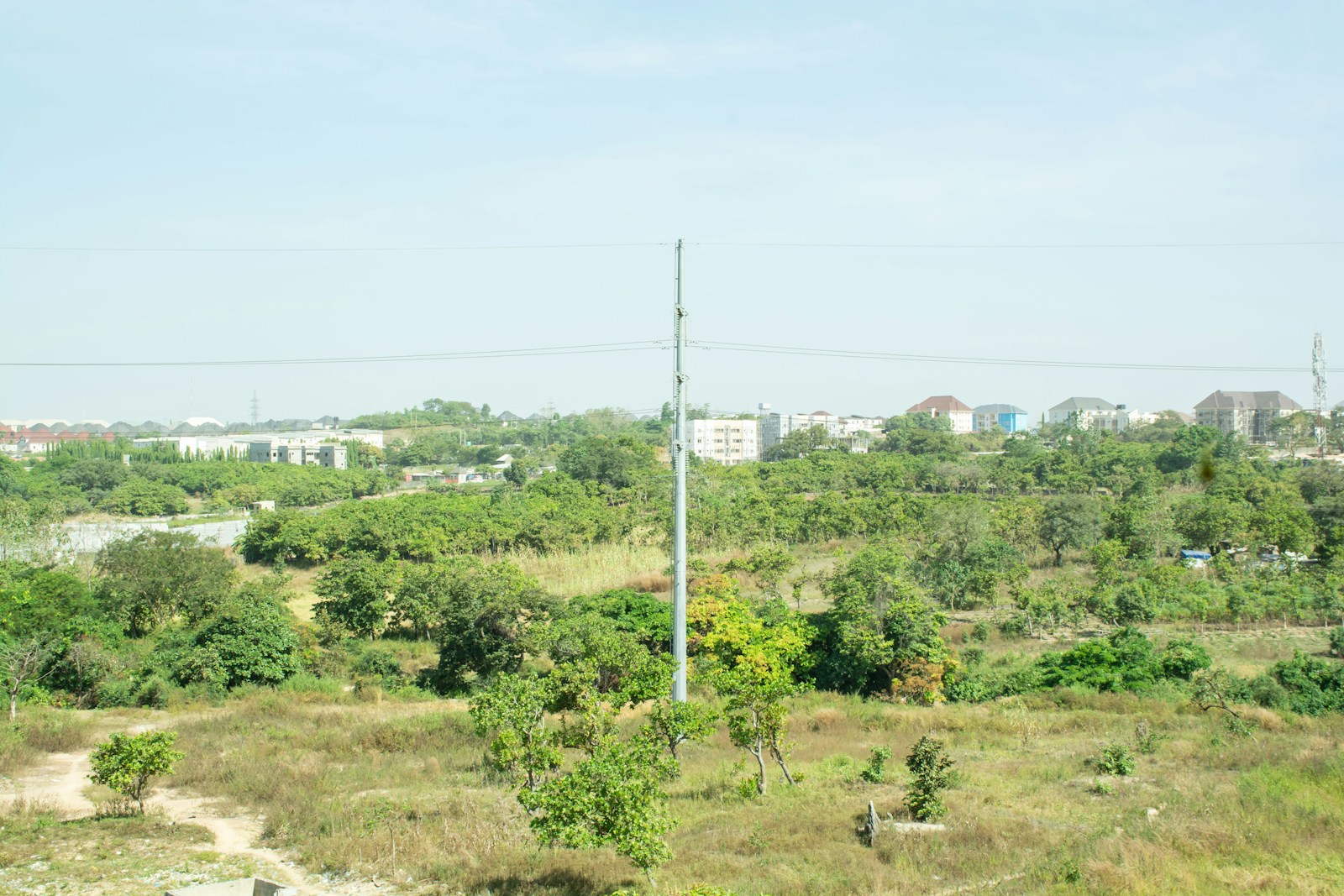 Open plot of land with houses in the background on the outskirts of Abuja, Nigeria, illustrating where to buy land by budget in 2026
