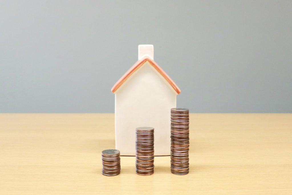 A model house beside stacks of coins on a table, illustrating Nigeria's 2026 FMBN mortgage reforms and home financing