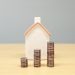 A small wooden house model beside stacks of coins, illustrating fractional property ownership in Nigeria in 2026