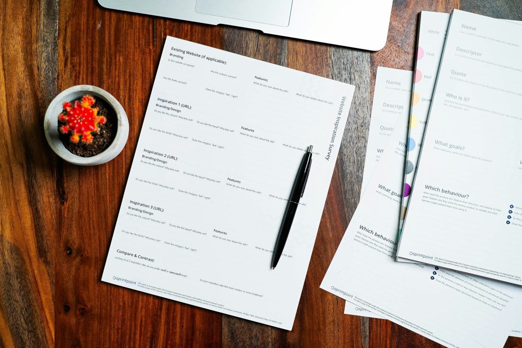 Property documents and a pen on a wooden desk, representing the land title papers a Nigerian buyer must verify before paying