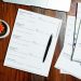 Property documents and a pen on a wooden desk, representing the land title papers a Nigerian buyer must verify before paying