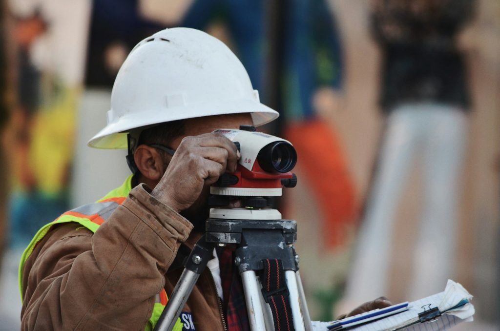 A surveyor's level standing on open land, illustrating the land verification checks that prevent costly buying mistakes in Nigeria
