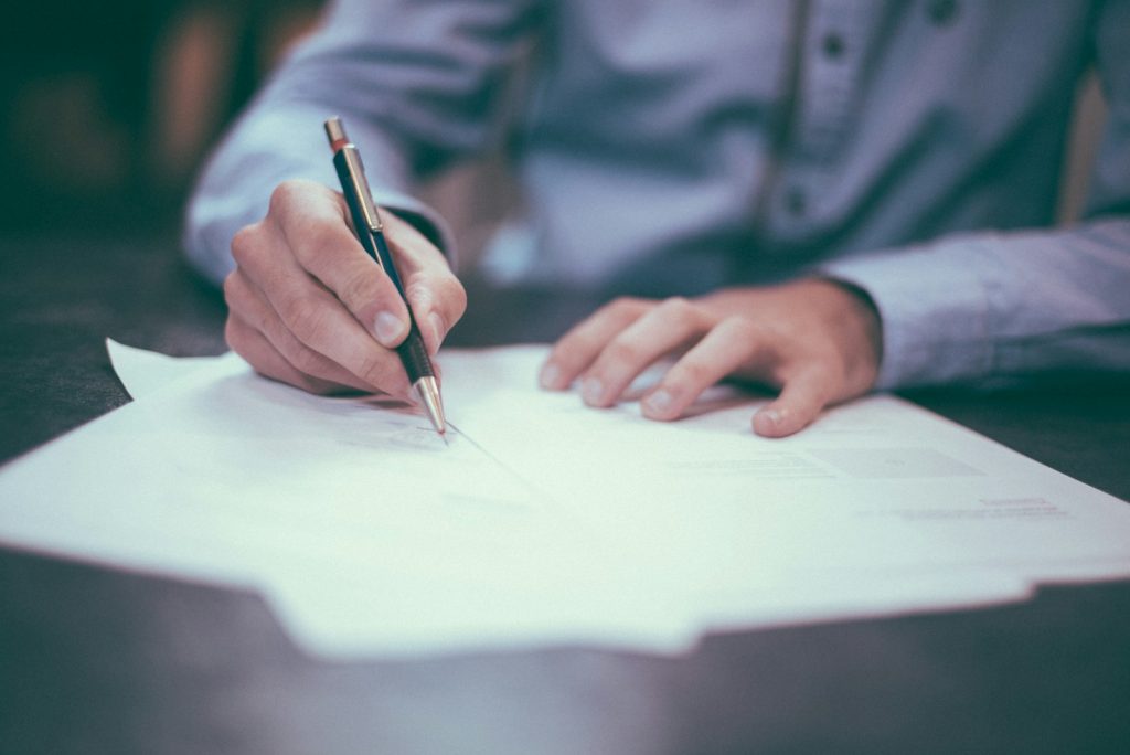 A property contract and pen on a desk, illustrating Nigerian land titles — C of O, Gazette, excision and Governor's Consent explained for 2026