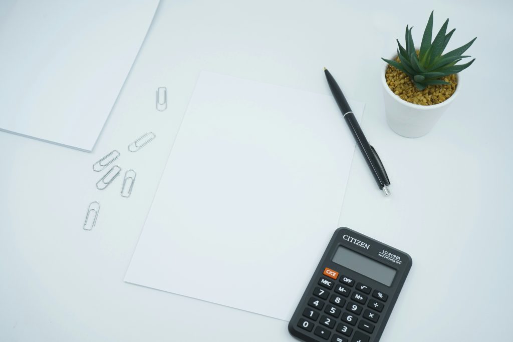 A calculator, pen and paper on a desk representing the tax and fiscal costs a Nigerian property buyer must budget in 2026