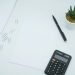 A calculator, pen and paper on a desk representing the tax and fiscal costs a Nigerian property buyer must budget in 2026