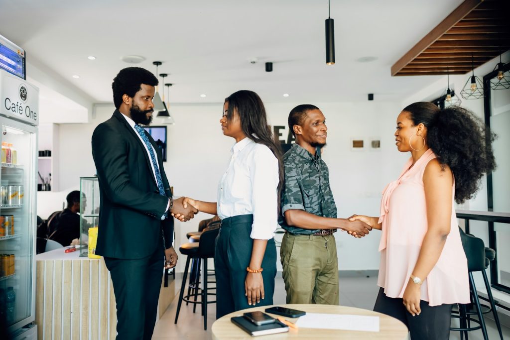 African business people shaking hands over a property agreement, illustrating estate-agent verification in Lagos