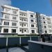 Front elevation of the four-storey apartment block in Ikeja GRA, Lagos, showing curved white balconies, a dark lift core and the gated forecourt