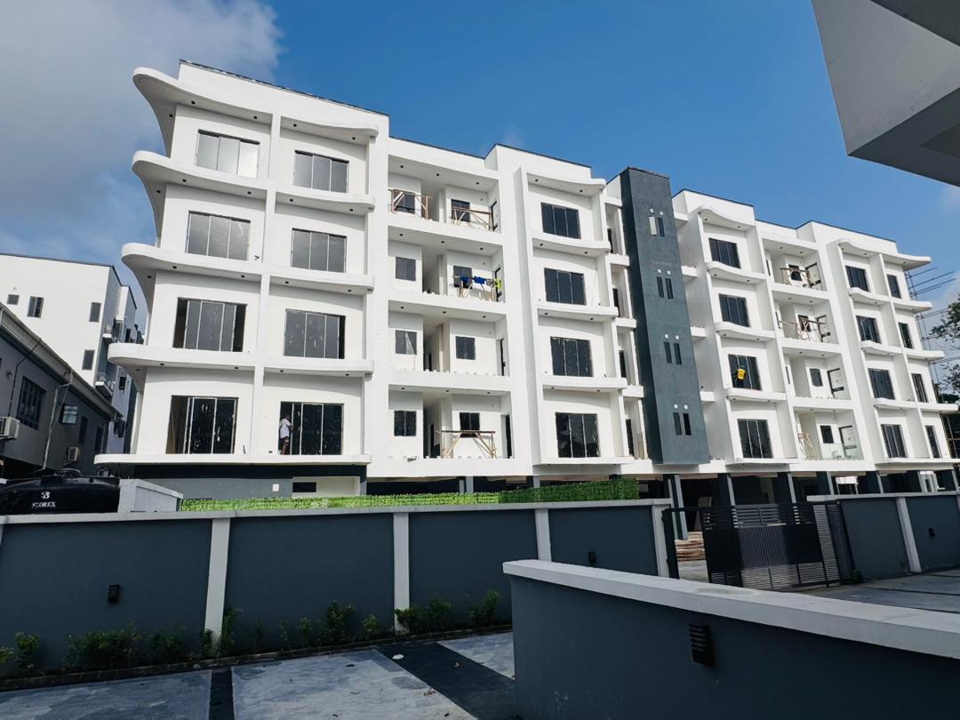 Four-storey apartment block in Ikeja GRA, Lagos, with curved white balconies and a gated forecourt