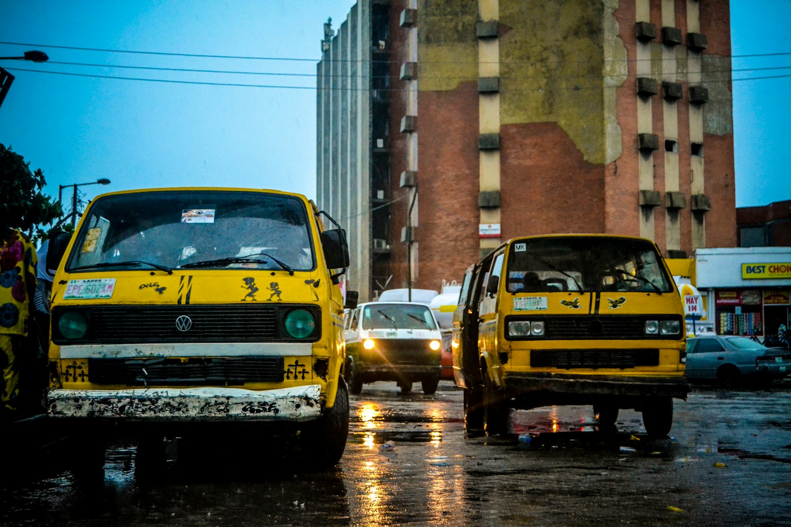 A yellow danfo bus on a busy Lagos street lined with traders