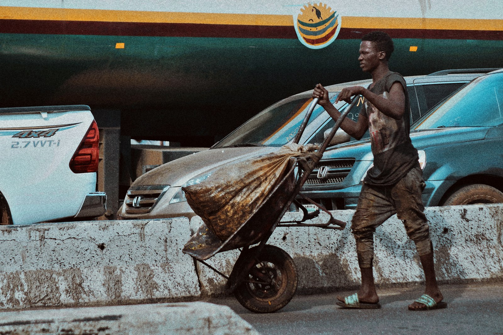 A porter pushing a wheelbarrow of goods through a busy Lagos market