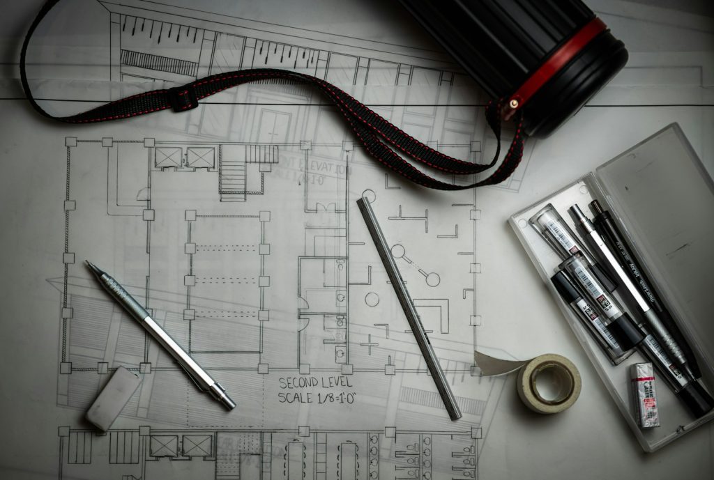 A land survey plan with drafting pencils and a ruler, representing charting and title verification for Nigerian land, 2026