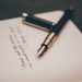 A fountain pen resting on a document, representing a power of attorney used to buy land in Nigeria from abroad.